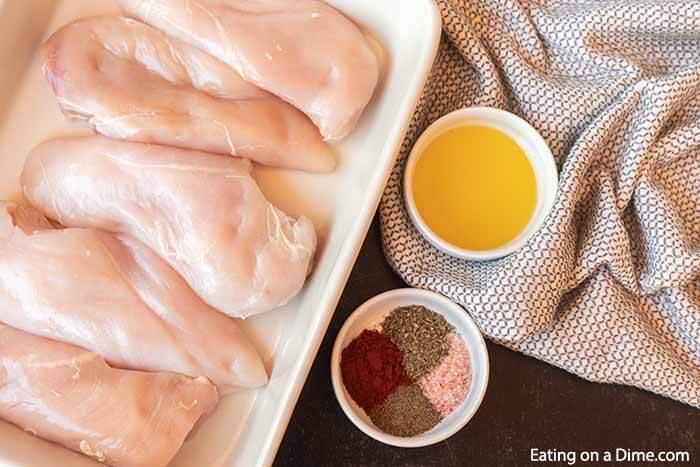 Ingredients - Chicken breast on a plate, with a bowl of oil and a bowl of seasoning