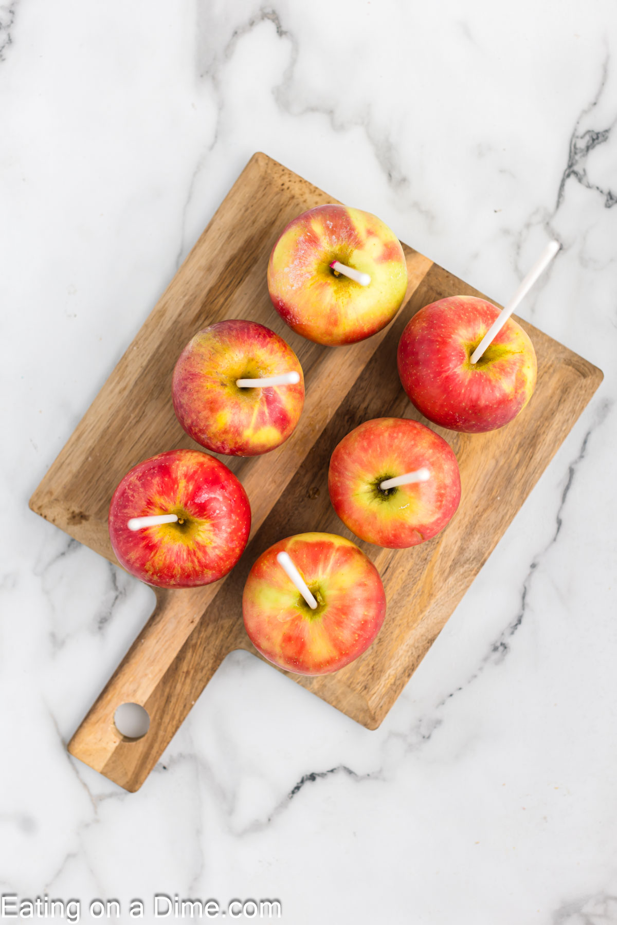 Inserting sticks into apples that are on a cutting board