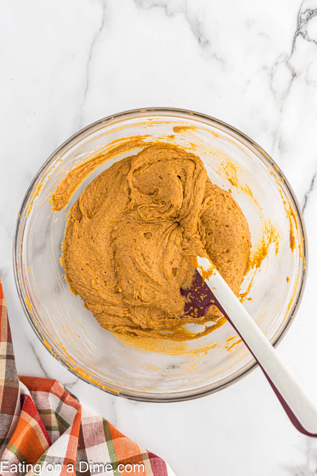 Combining the pumpkin cupcake ingredients in a bowl with a spoon