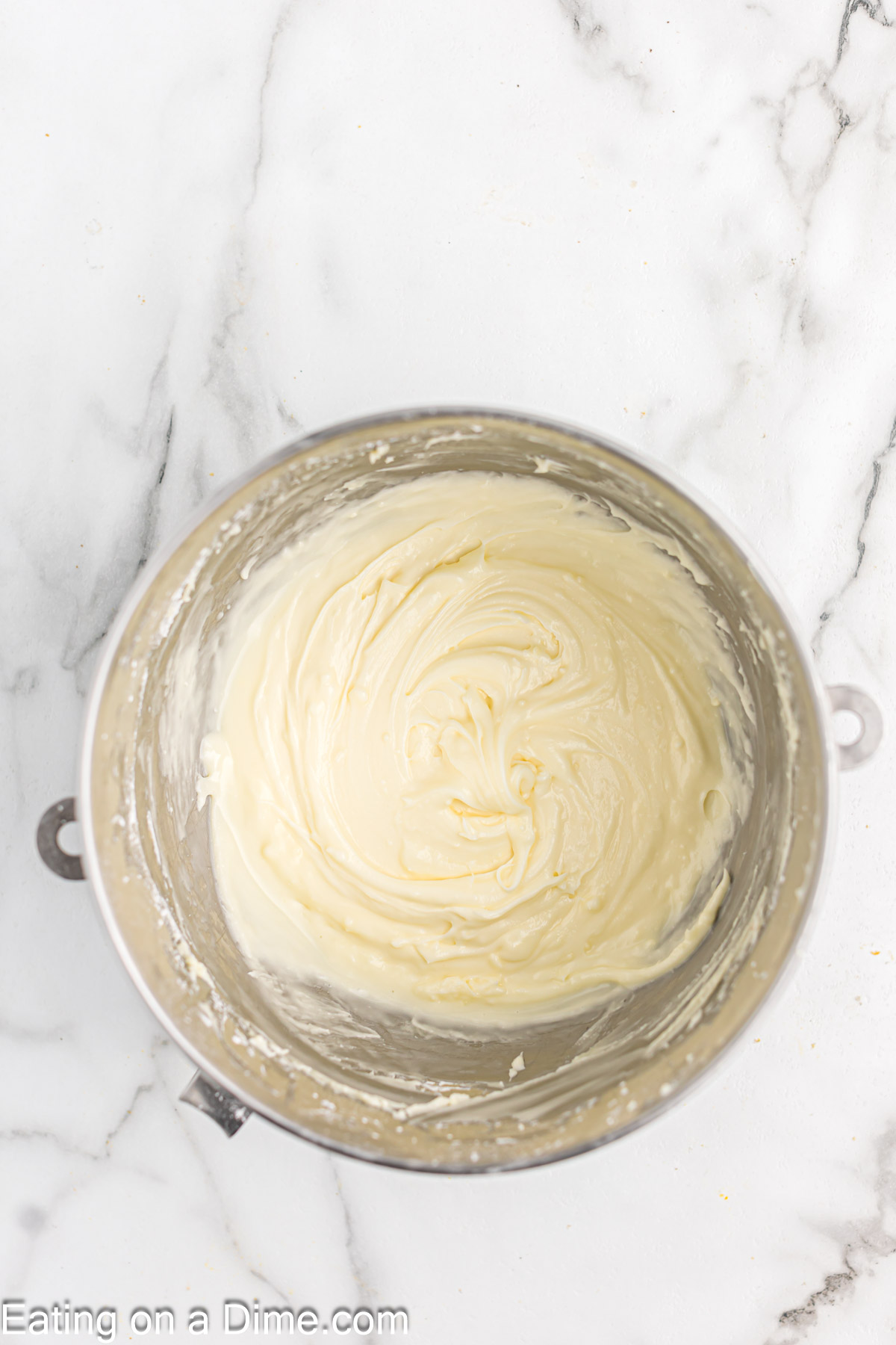 Combining the cream cheese frosting ingredients in a bowl