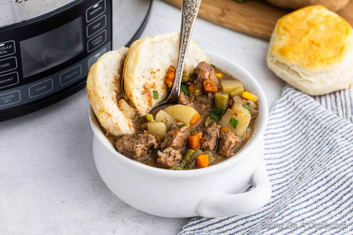 Beef pot pie in a bowl with a side of biscuits.