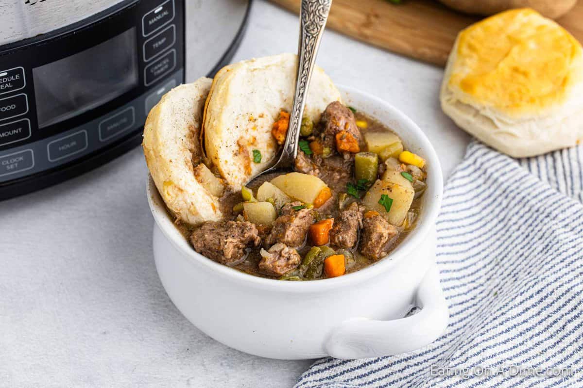 Small white dish of beef pot pie with a biscuit on the side