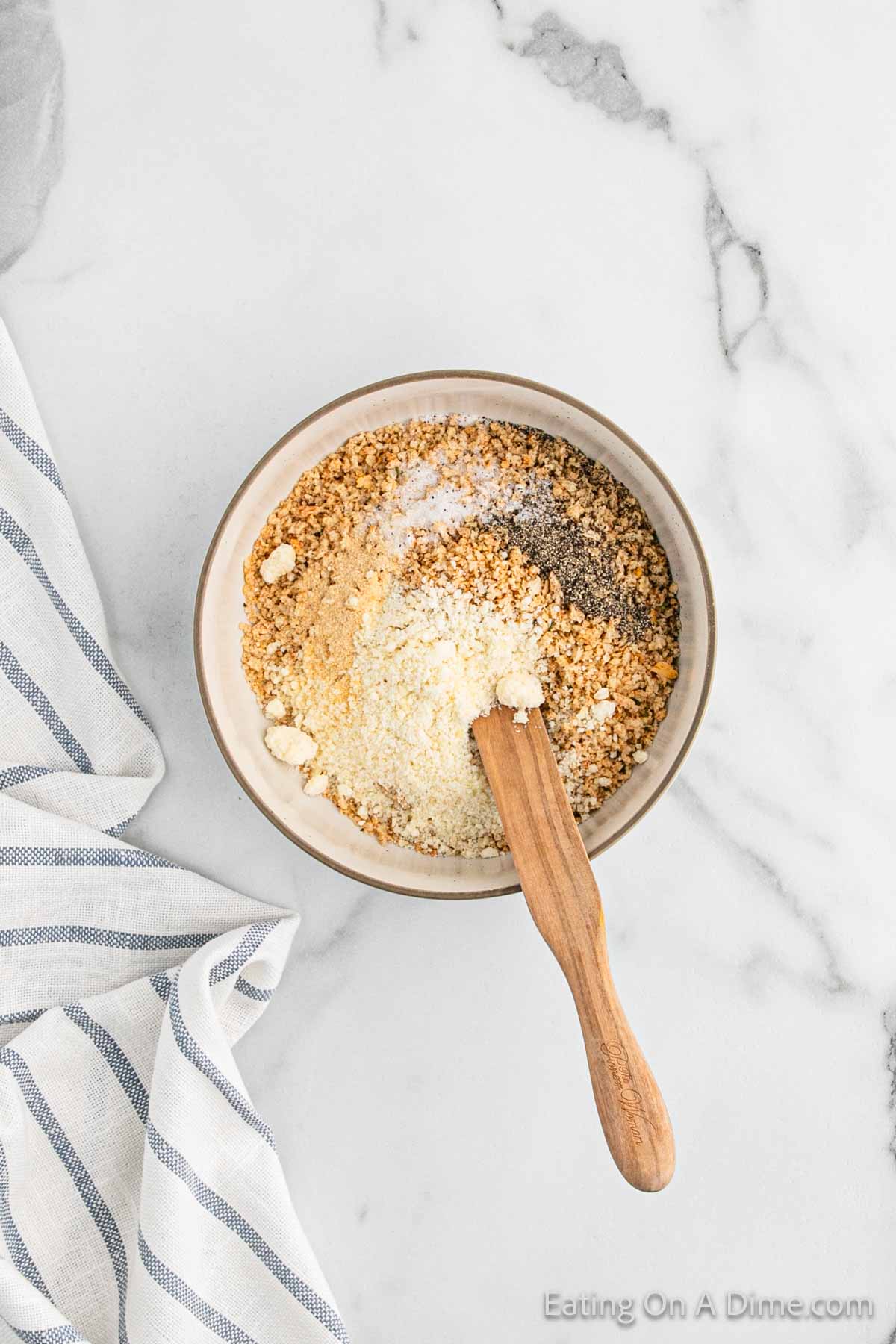 Combining the breadcrumbs and spice together in a bowl with a wooden spoon