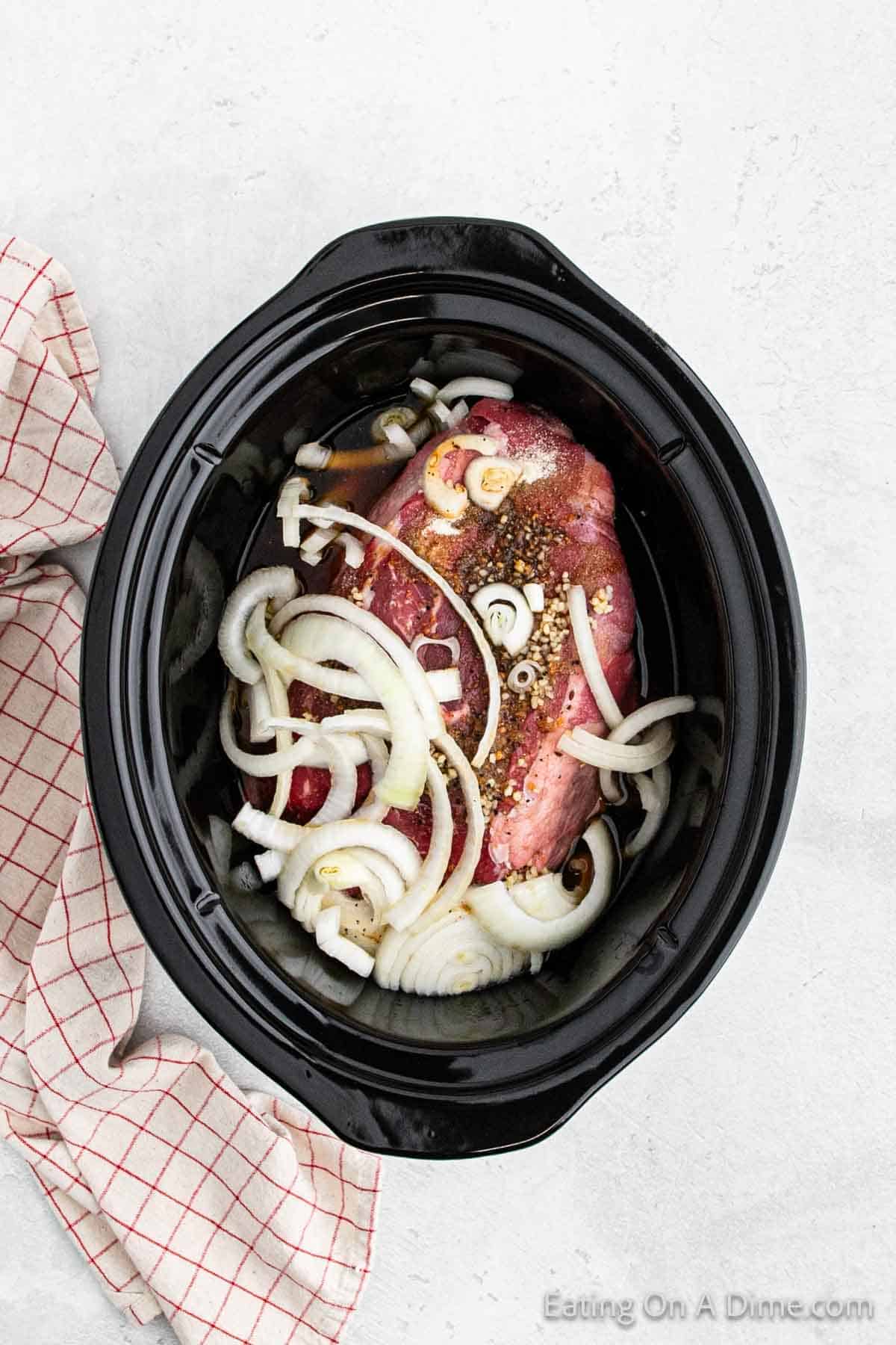 Adding the beef, onions and sauce to the slow cooker