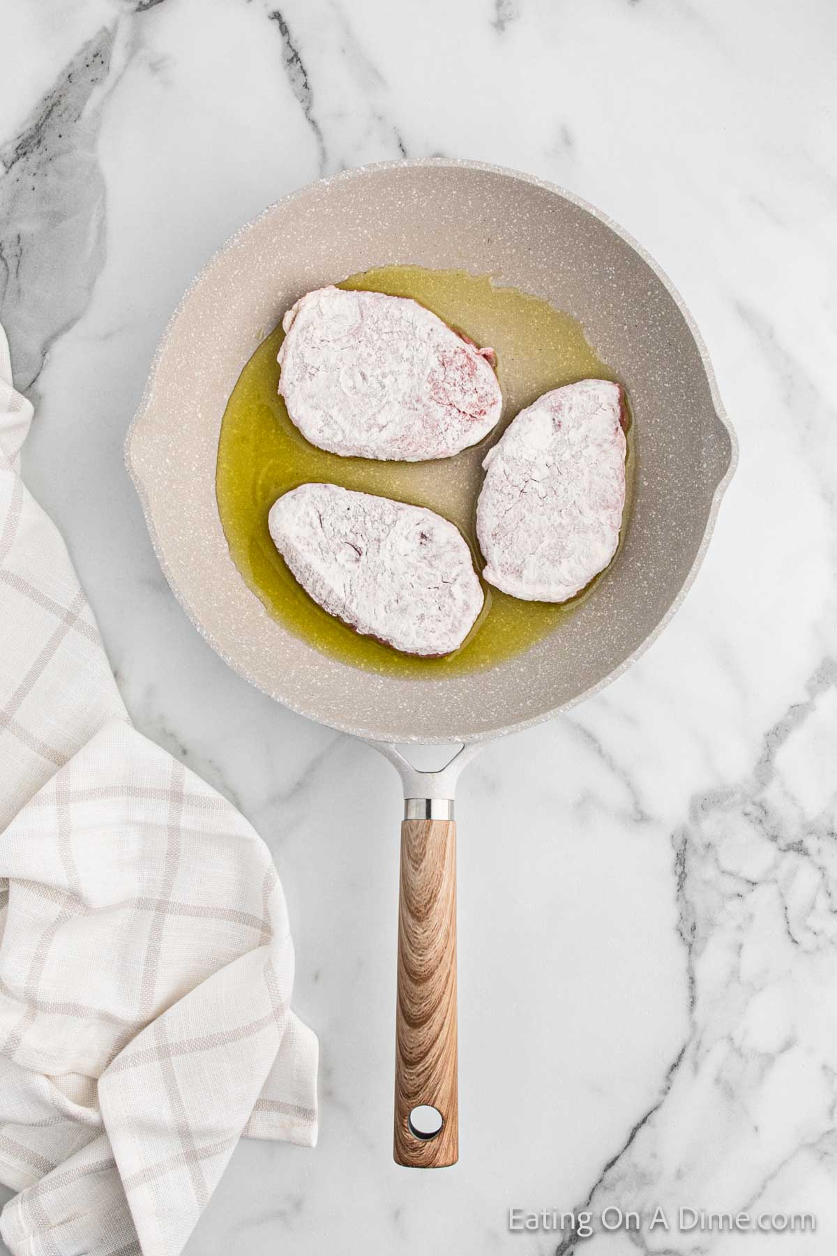 Cooking floured covered steak in a skillet with oil