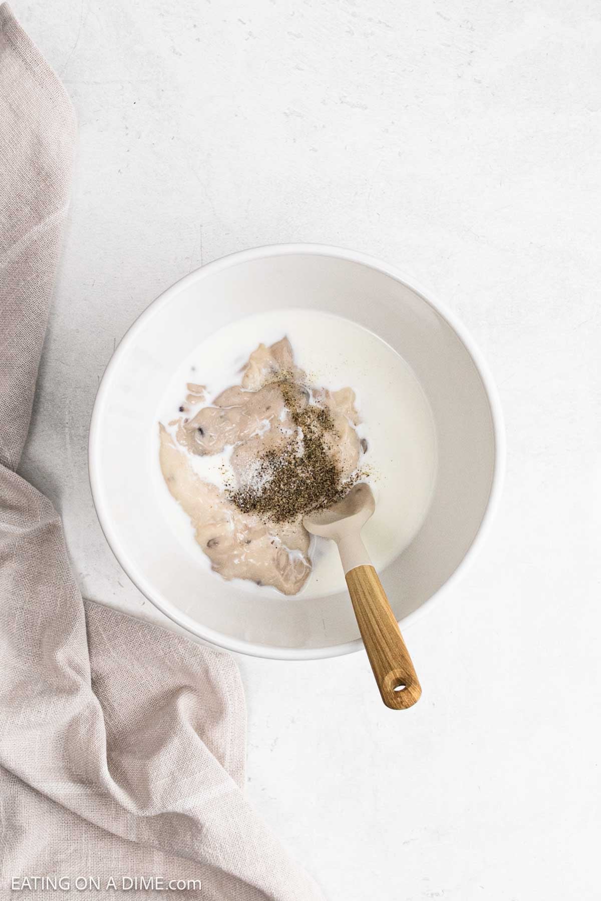 Combining milk, cream of mushroom soup and spices in a bowl.
