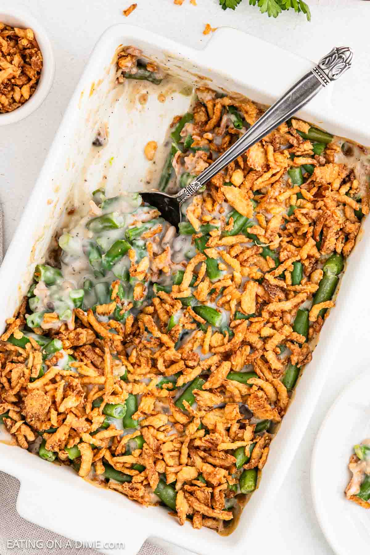 Green beans mixed with a creamy mixture topped with French fried onions in a baking dish.