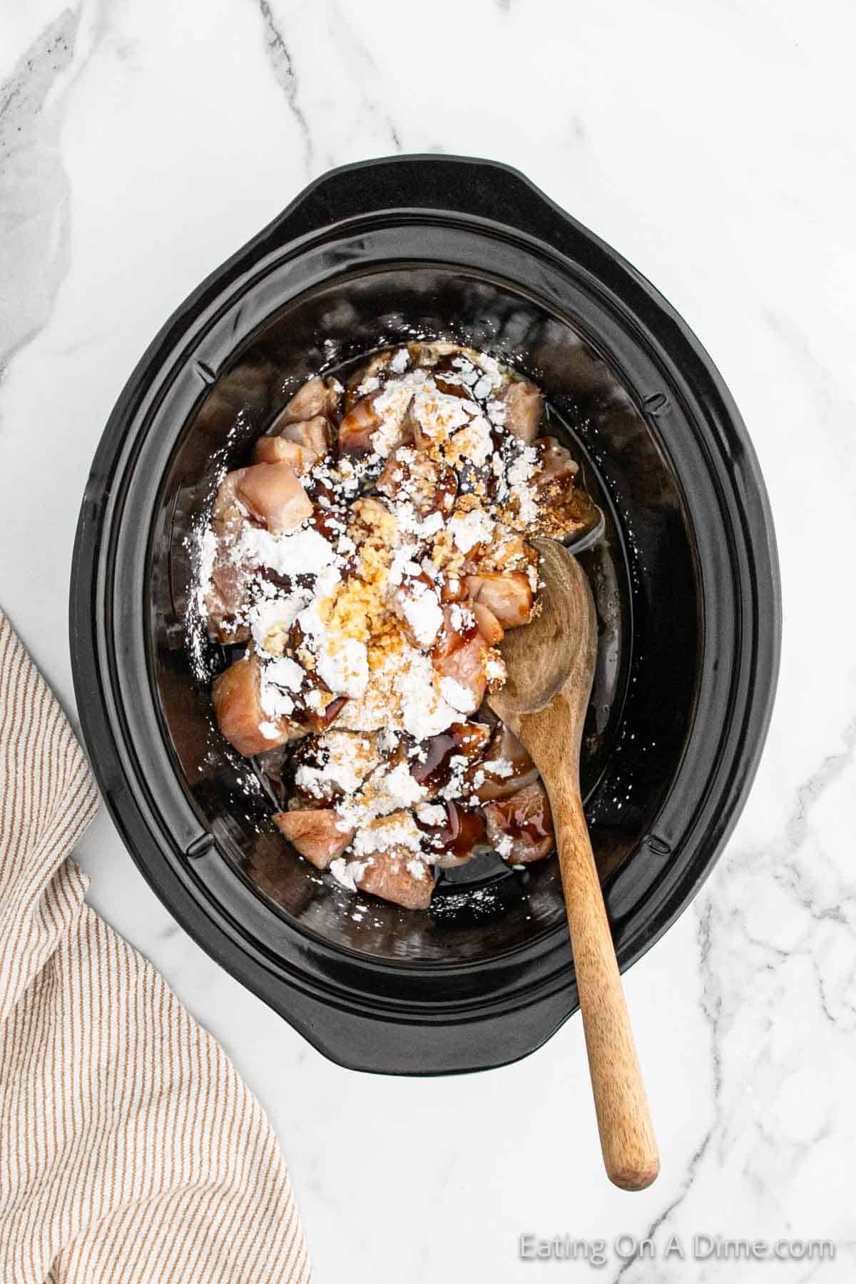 Diced chicken in the slow cooker topped with cornstarch, olive oil, chicken broth, hoisin sauce, soy sauce, rice vinegar, sesame oil, garlic, ginger