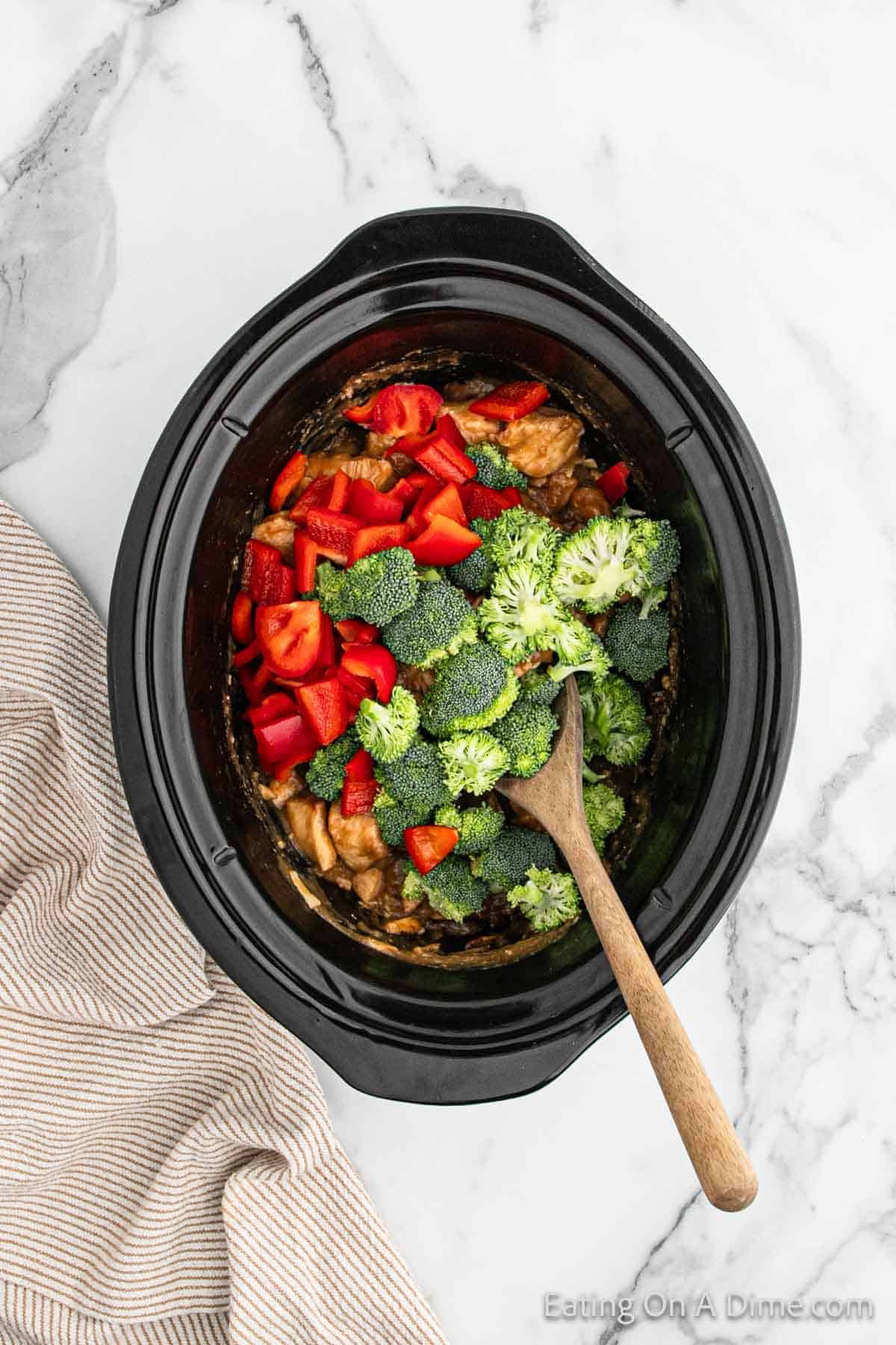 Topping the cooked chicken mixture with red bell pepper and chopped broccoli