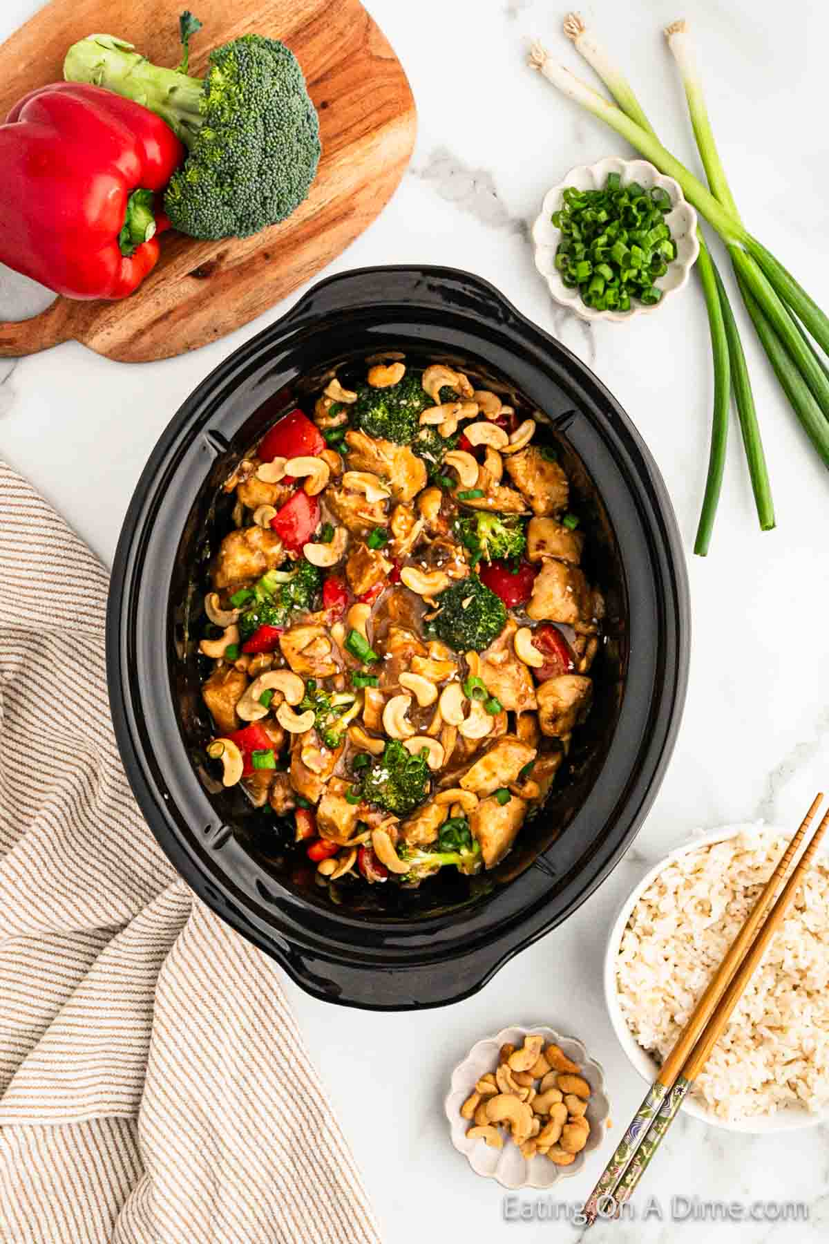 Topping the cashews with chicken, broccoli and red bell peppers