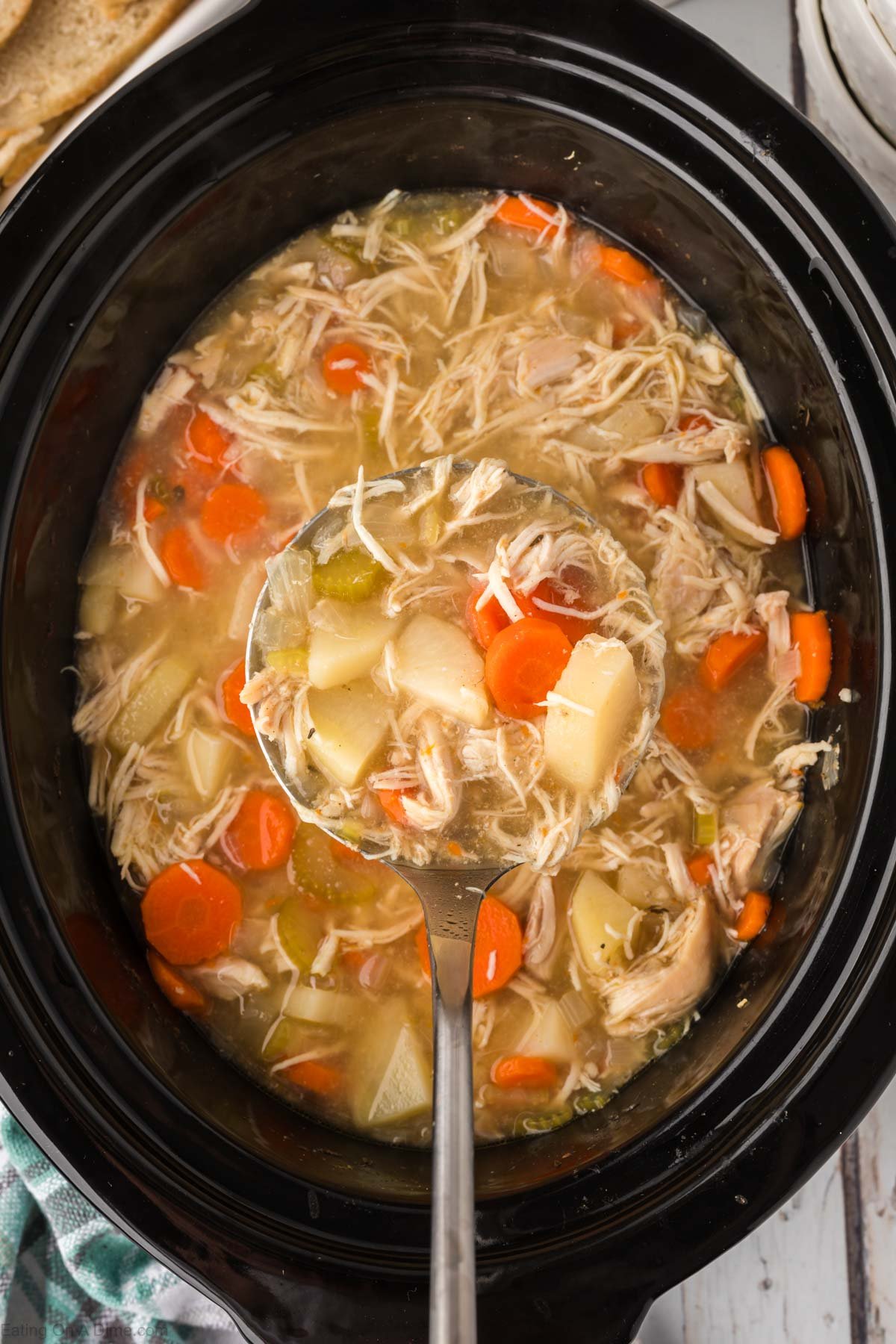 Chicken stew in the slow cooker with a serving on a ladle