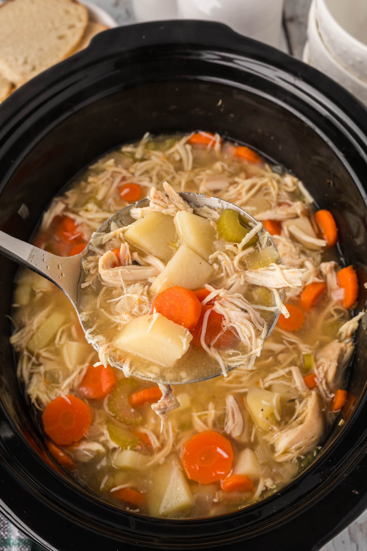Chicken stew in the slow cooker with a serving on the ladle