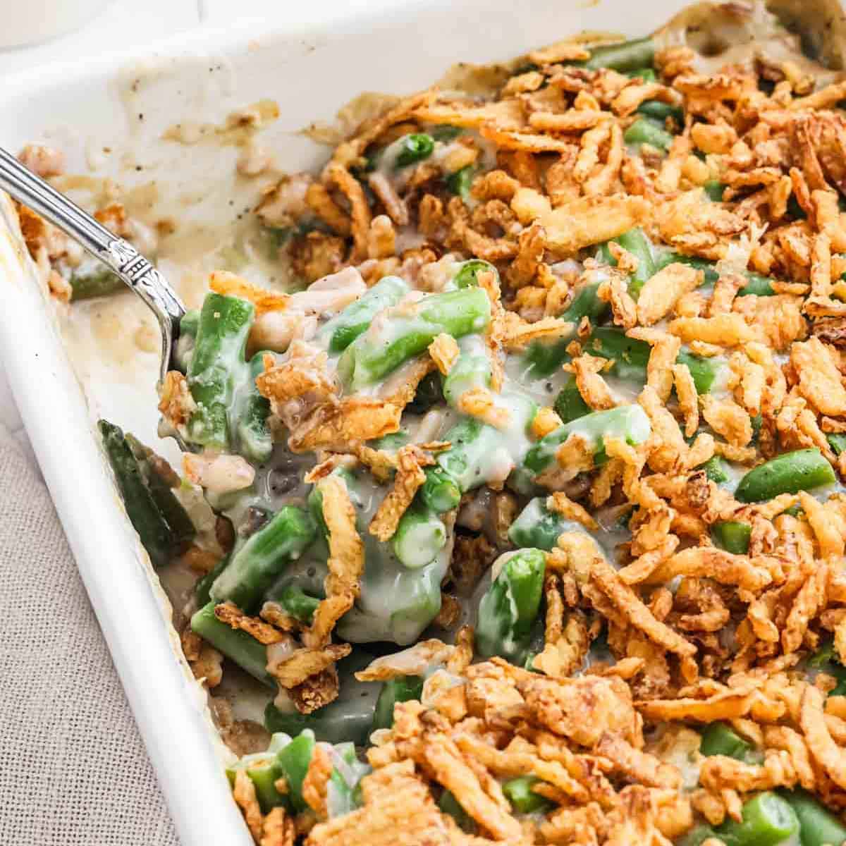 Green beans mixed with a creamy mixture topped with crispy fried onions in a baking dish.