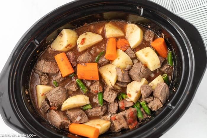 Close up image of beef stew in crockpot in process. 