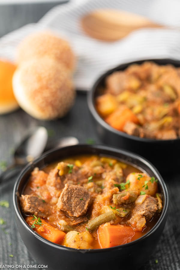 Close up image of a bowl of beef stew with two spoons. 