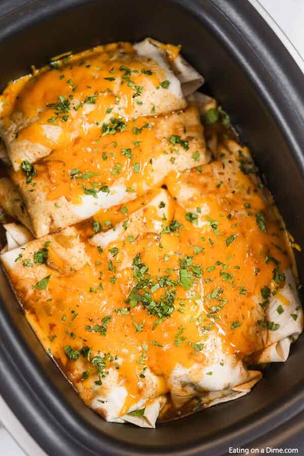 Crock pot smothered burritos will be a family favorite.  Tender beef smothered with cheese and more make this green chili recipe so flavorful. The crockpot makes it simple and easy. This crock pot Mexican recipe for smothered burritos has the best green sauce. #eatingonadime #crockpotsmotheredburritos #slowcooker