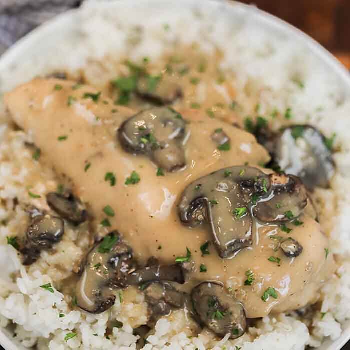 Crock pot smothered chicken with mushrooms is a really easy recipe with lots of tender chicken with gravy. Creamy Mushroom Chicken is amazing over rice and the entire dinner is effortless.  Try easy chicken and mushrooms for the best slow cooker meal. Smothered chicken with cream of mushroom, onion and more come together for a delicious meal. Crock Pot Smothered Chicken is an easy and delicious weeknight meal. #eatingonadime #crockpotsmotheredchicken #mushroomsmotheredchicken