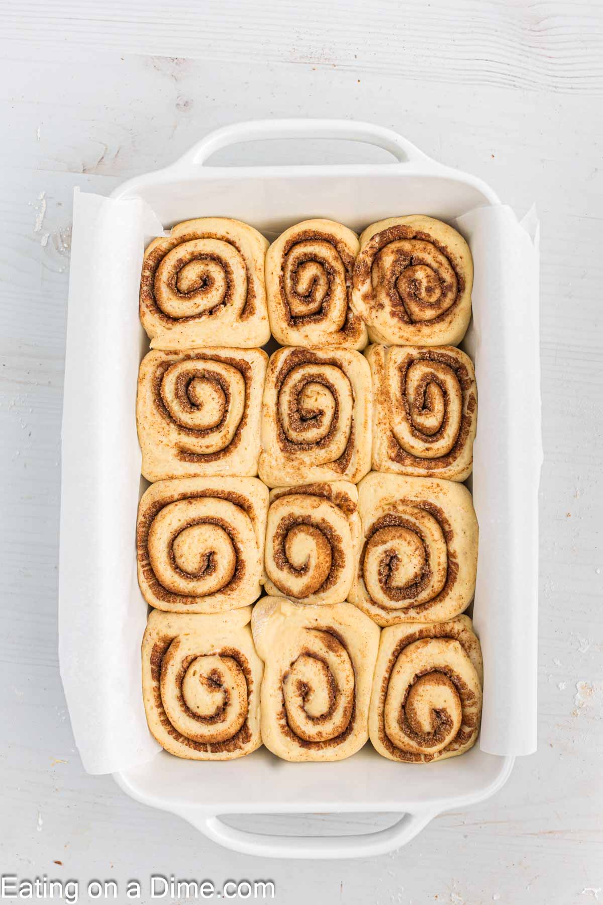 Allowing the cinnamon roll dough to double in size in a baking dish