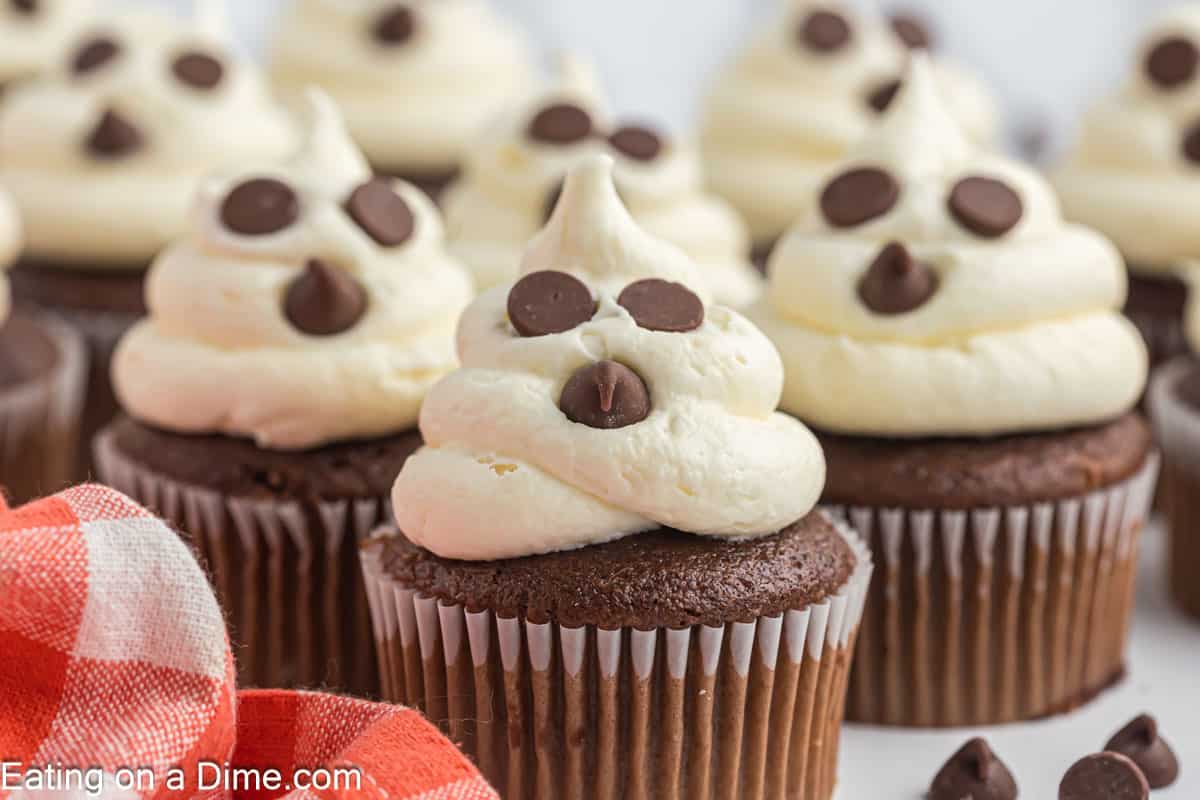 Ghost cupcakes topped with white frosting and chocolate chips.