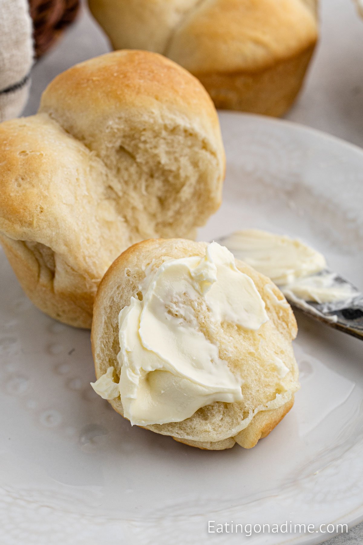 Topping the homemade rolls with butter on a plate
