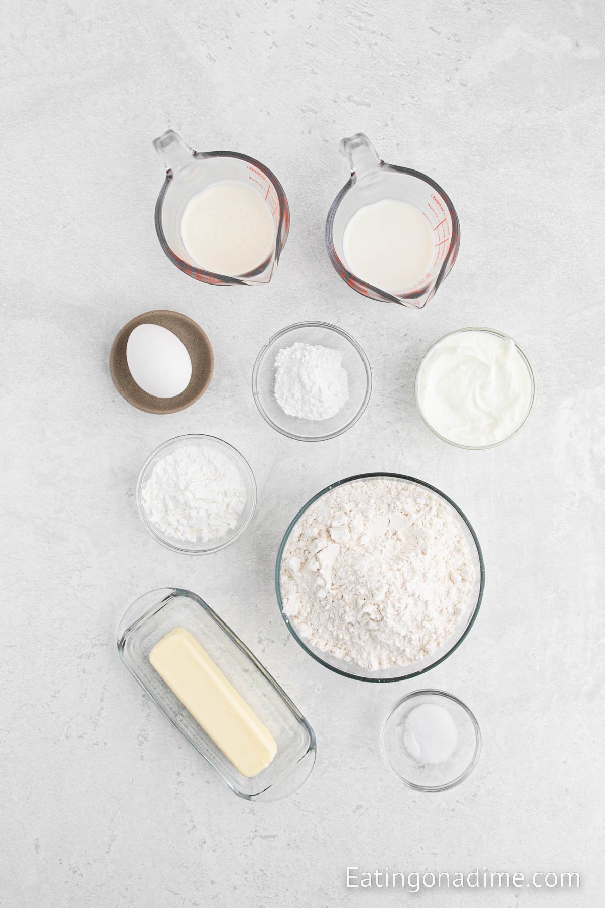 Homemade biscuit ingredients - flour, cornstarch, baking powder, salt, salted butter, greek yogurt, heavy cream, milk, egg