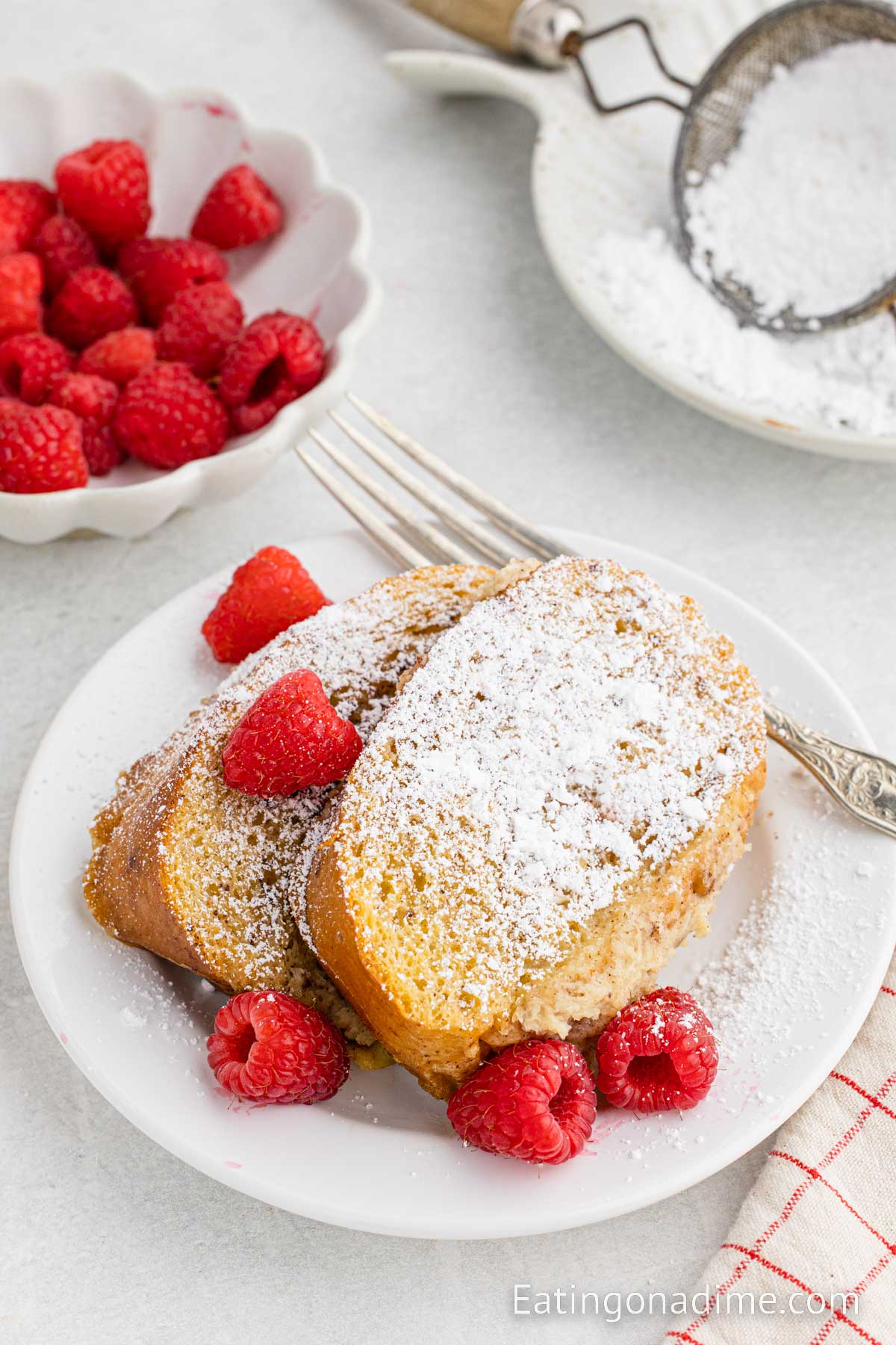 Slice of French Bread on a plate topped with powdered sugar and fresh berries