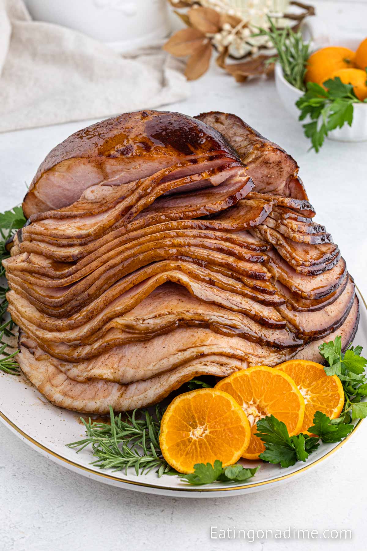Slice spiral ham on a platter with fresh herbs and slice oranges