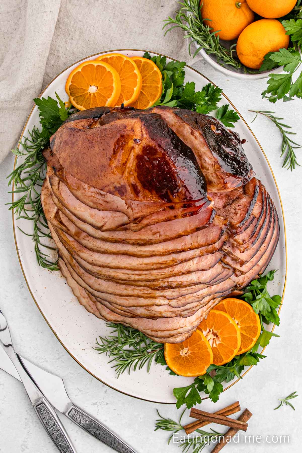 Spiral Ham sliced on a platter with fresh herbs and slice oranges