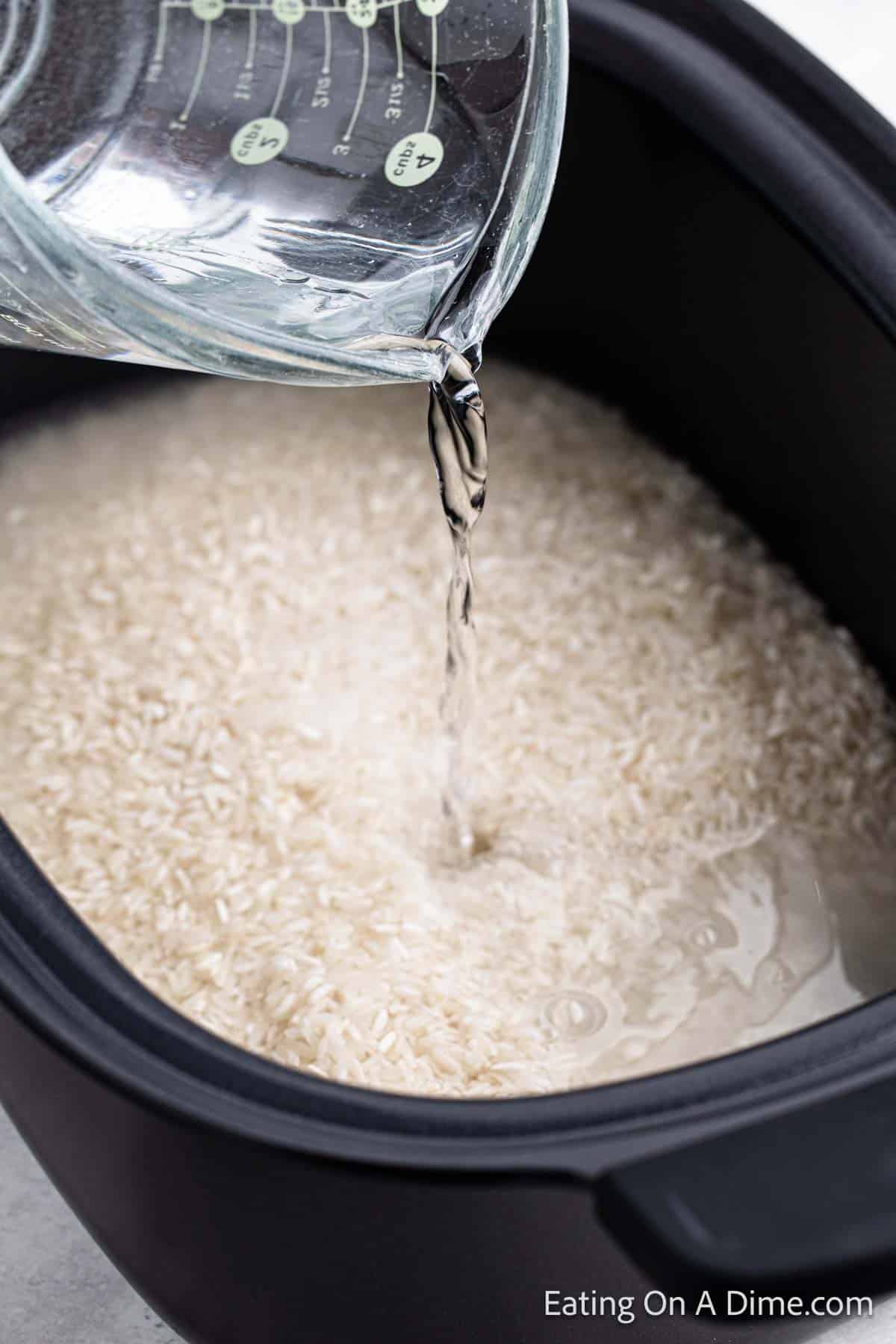 Pouring the water into the slow cooker on top of the white rice