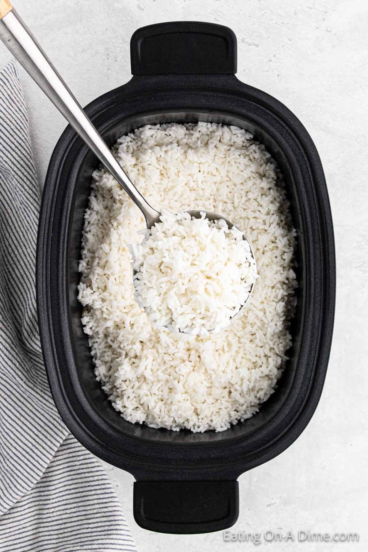 Cooked white rice in the slow cooker with a serving on a silver spoon