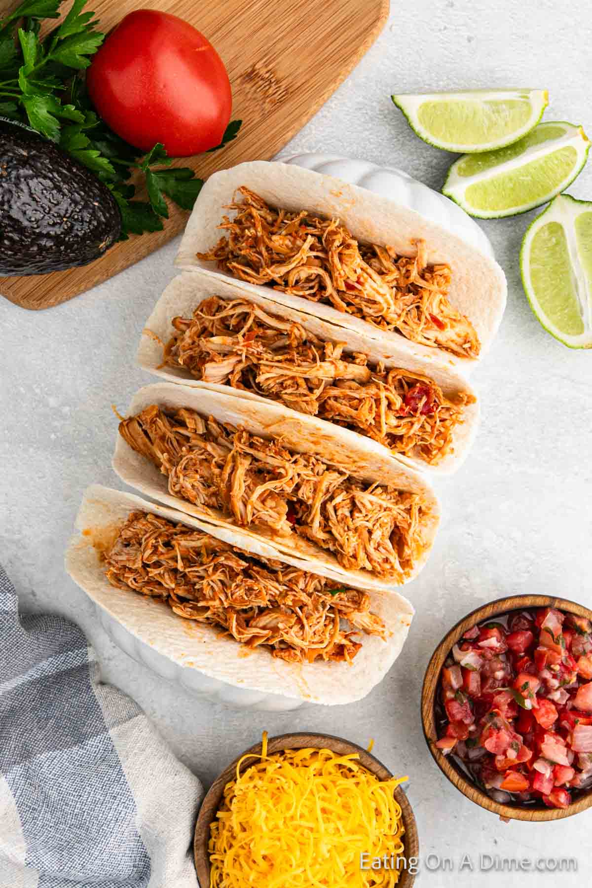 Shredded chicken placed in flour tortillas with a side of fresh limes