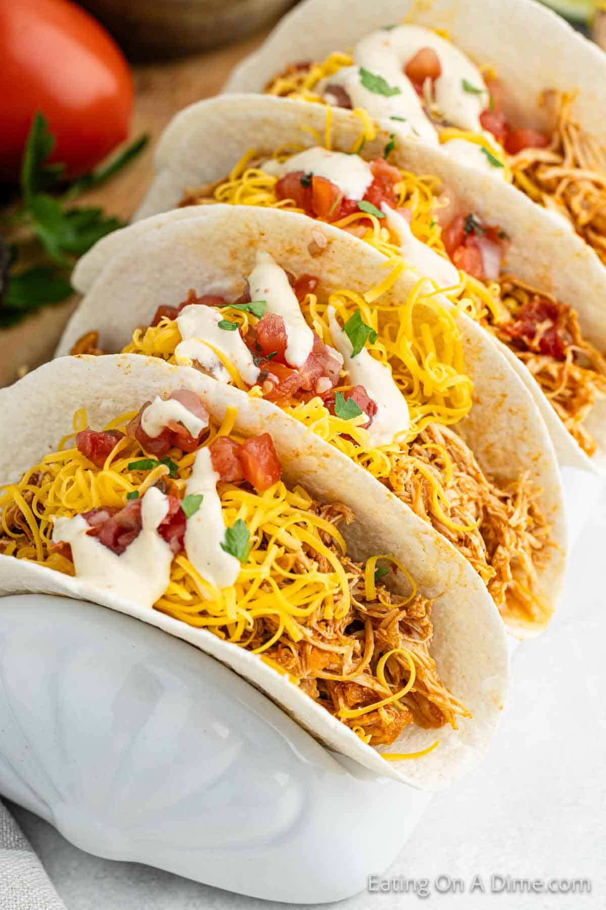 Shredded Chicken tacos in flour tortillas topped with shredded cheese, tomatoes and sour cream