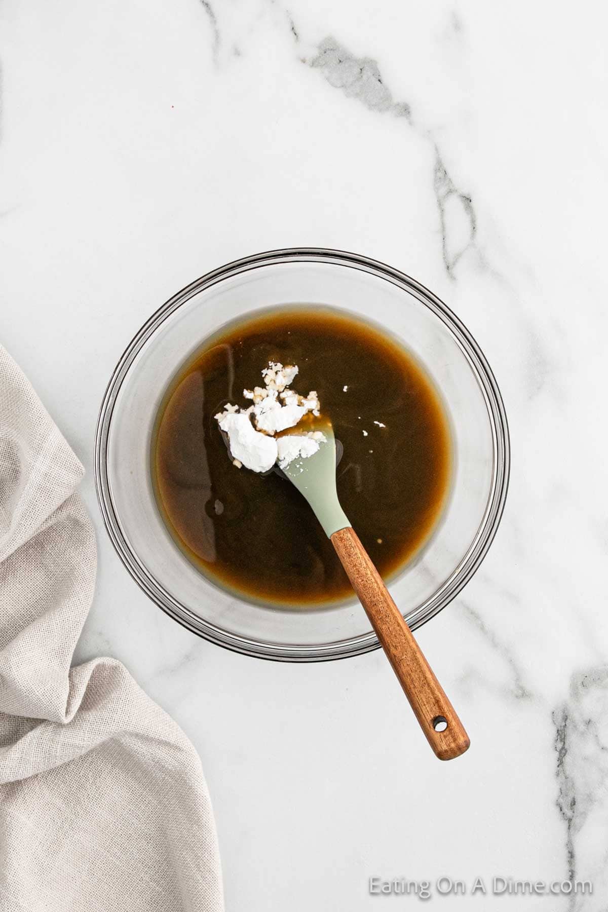 Combining the chicken broth, soy sauce, balsamic vinegar, honey, and cornstarch in a bowl with a wooden spoon