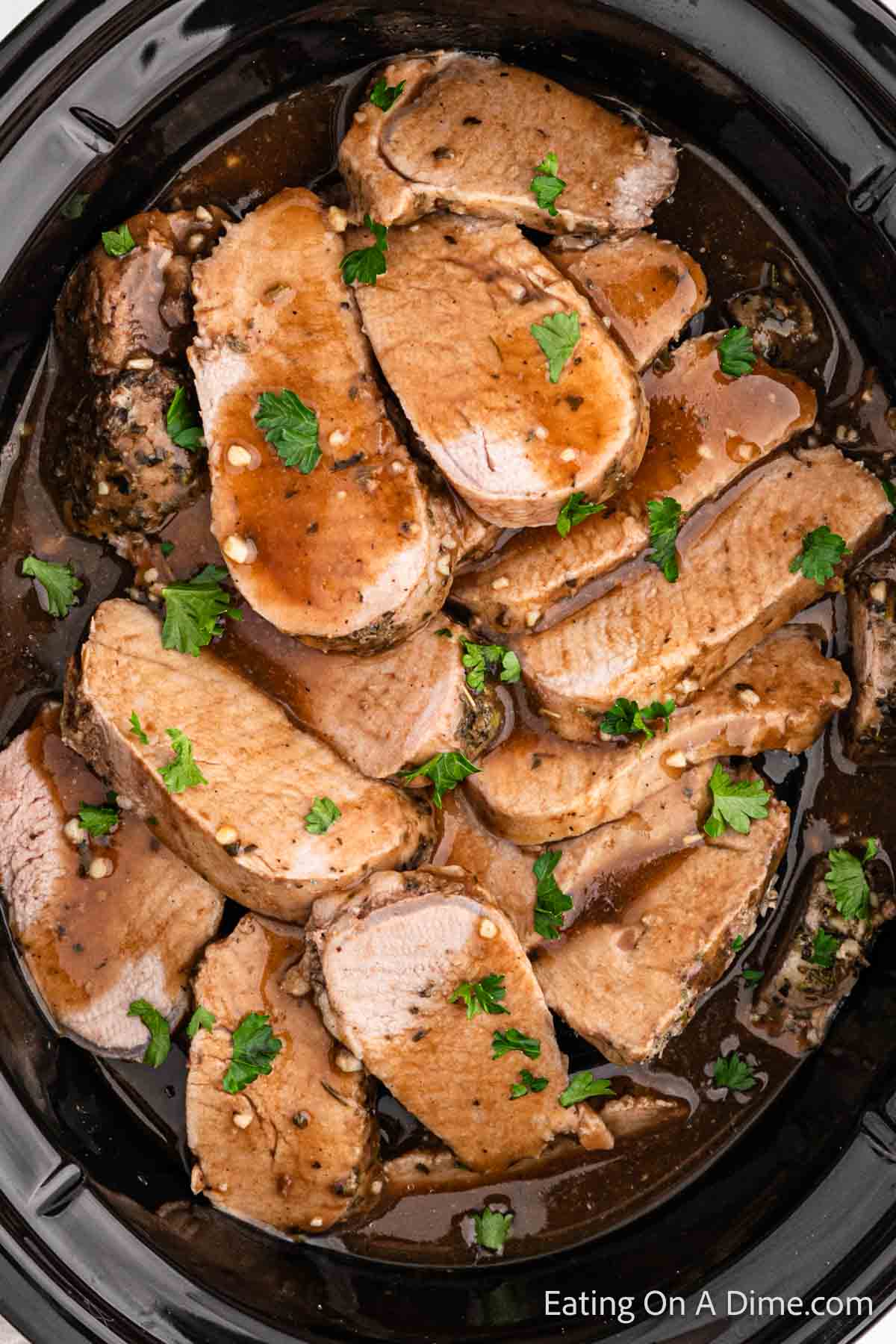 Slice pork tenderloin in the slow cooker with sauce and fresh parsley