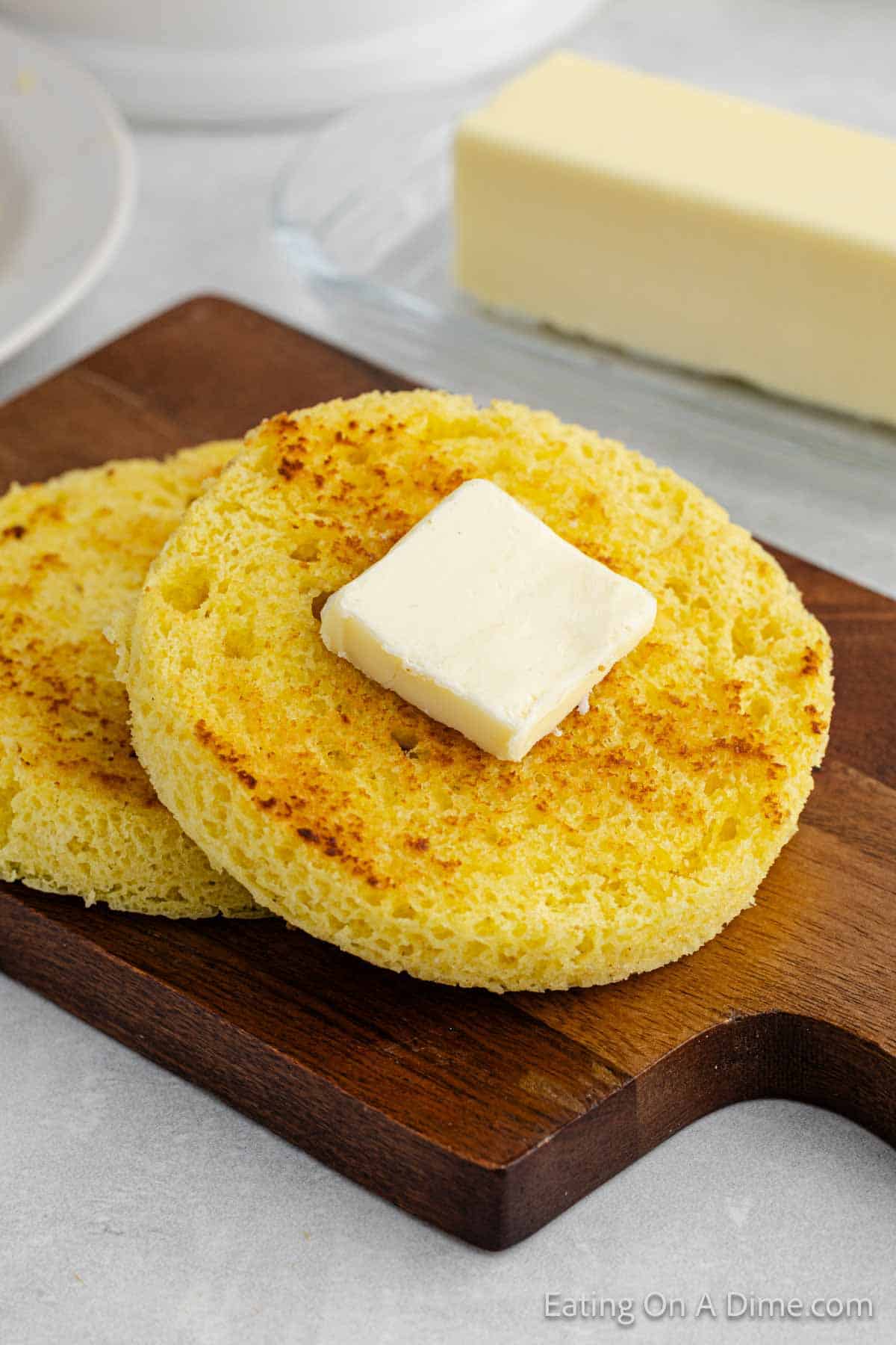 Keto bread sliced on a cutting board topped with butter