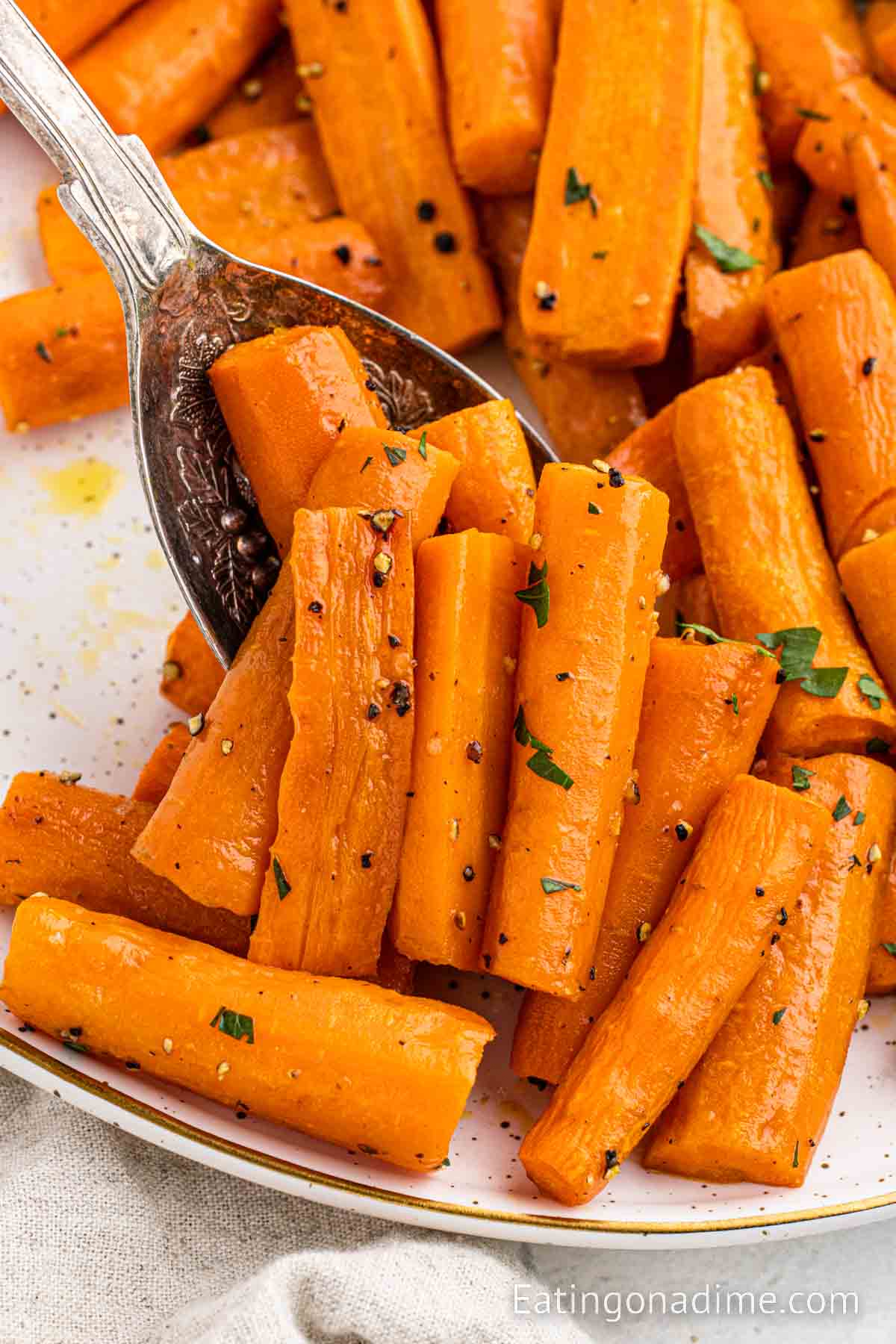 Roasted carrots on a baking sheet with a serving on a spoon