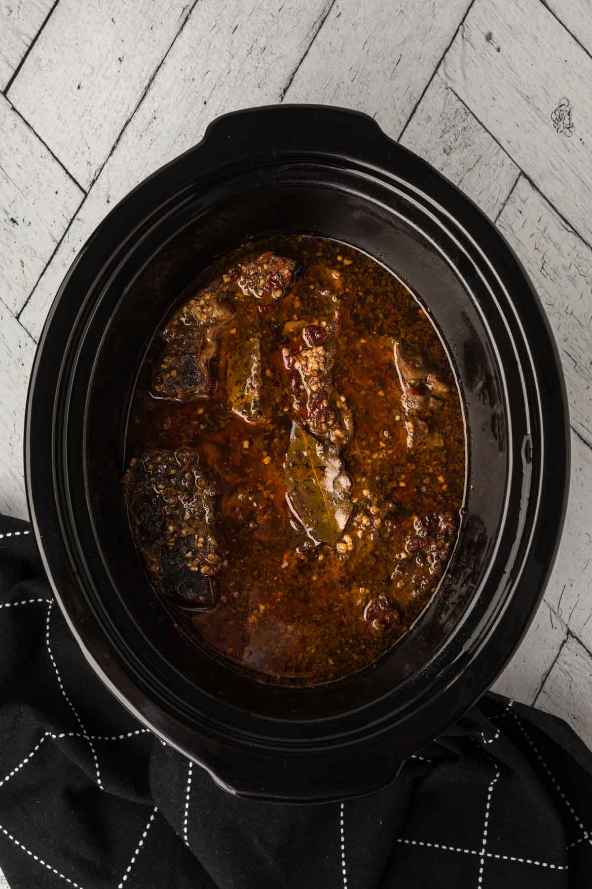 Cooked roast in a sauce and seasoning in the slow cooker