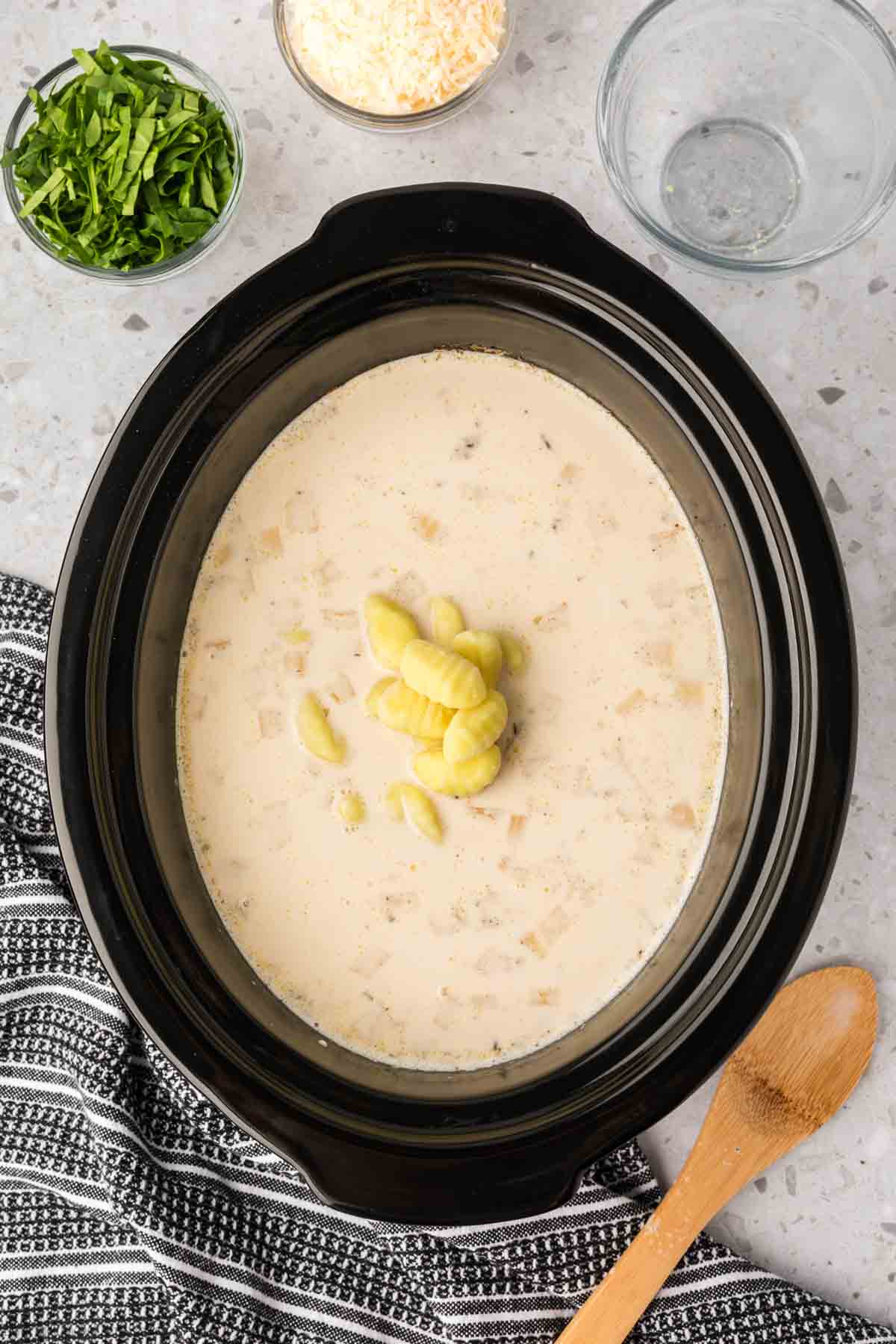 Adding in the potato gnocchi into the mixture in the slow cooker