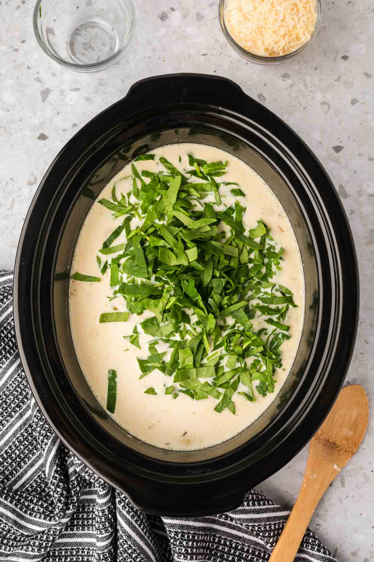 Stir in chopped spinach and parmesan cheese in the slow cooker