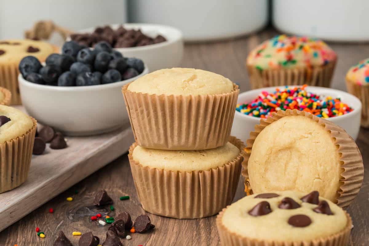Pancake Muffins with small bowls of blueberries, sprinkles and chocolate chips