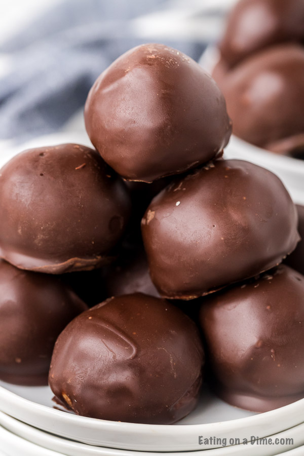 Chocolate covered peanut butter balls stacked on top of each other on a white plate. 