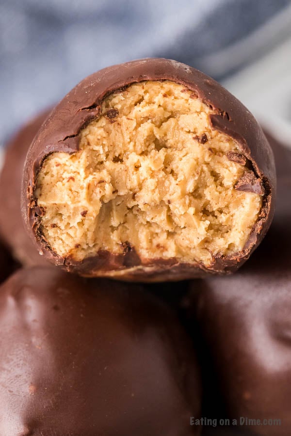 Close up of Chocolate covered peanut butter balls stacked on top of each other with a bite taken out of one of the balls.  