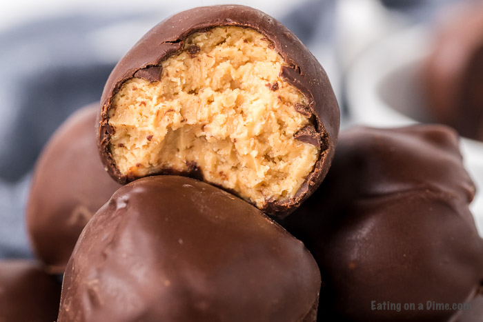 Chocolate covered peanut butter balls stacked on top of each other with a bite taken out of one of the balls.  