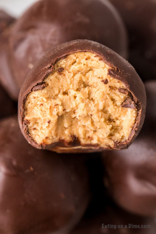 Chocolate covered peanut butter balls stacked on top of each other with a bite taken out of one of the balls.  