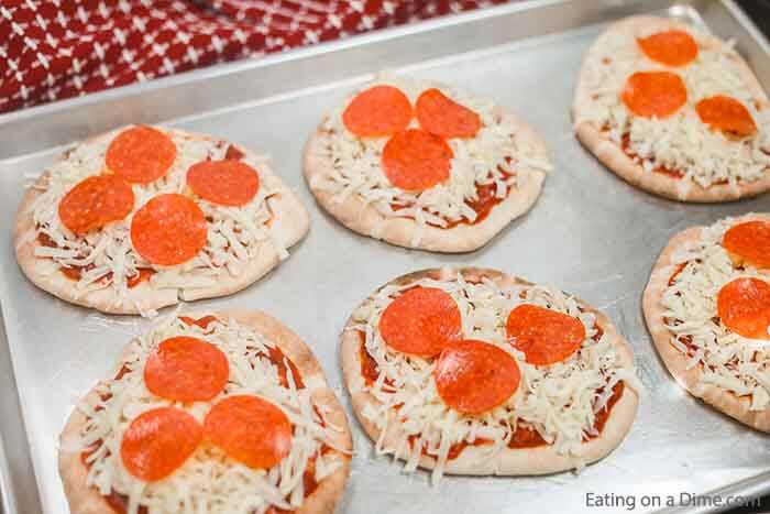 Enjoy this healthy Pita pizza recipe in minutes with the toppings of your choice. Skip takeout and make pita bread pizza for a quick and easy frugal dinner. Enjoy homemade mini pizza in the oven in minutes. The ideas are endless for pita pizza recipes and include buffalo chicken, BBQ Chicken and more. Kids love flatbread and pita pizza recipes. #eatingonadime #pitapizza #RecipesKids #healthycleaneating #lowcalorie 