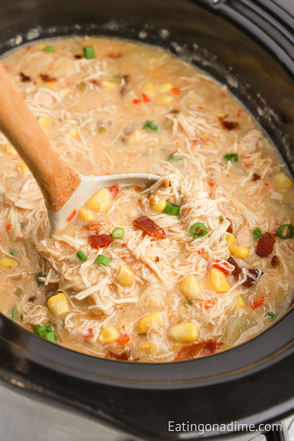chicken corn chowder soup in the crock pot with a spoon