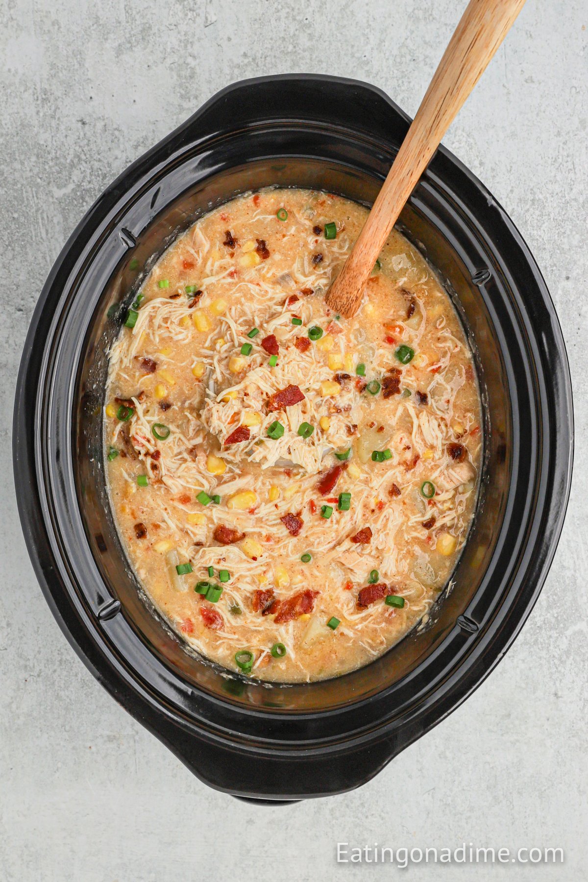 Enjoy delicious Crock pot chicken corn chowder recipe with hardly any work. Come home to the best comfort food when you make chicken corn chowder! This healthy slow cooker recipe is easy, cheesy and the best soup. Learn how to make homemade Crock pot chicken corn chowder that is so creamy. #eatingonadime #chickenandcornchowder #souprecipes #soupcrockpot #CrockPotEasy #Crockpotslowcooker #souphealthy #crockpot #chickenandcornchowdercrockpot Corn Chowder in the slow cooker with a spoon