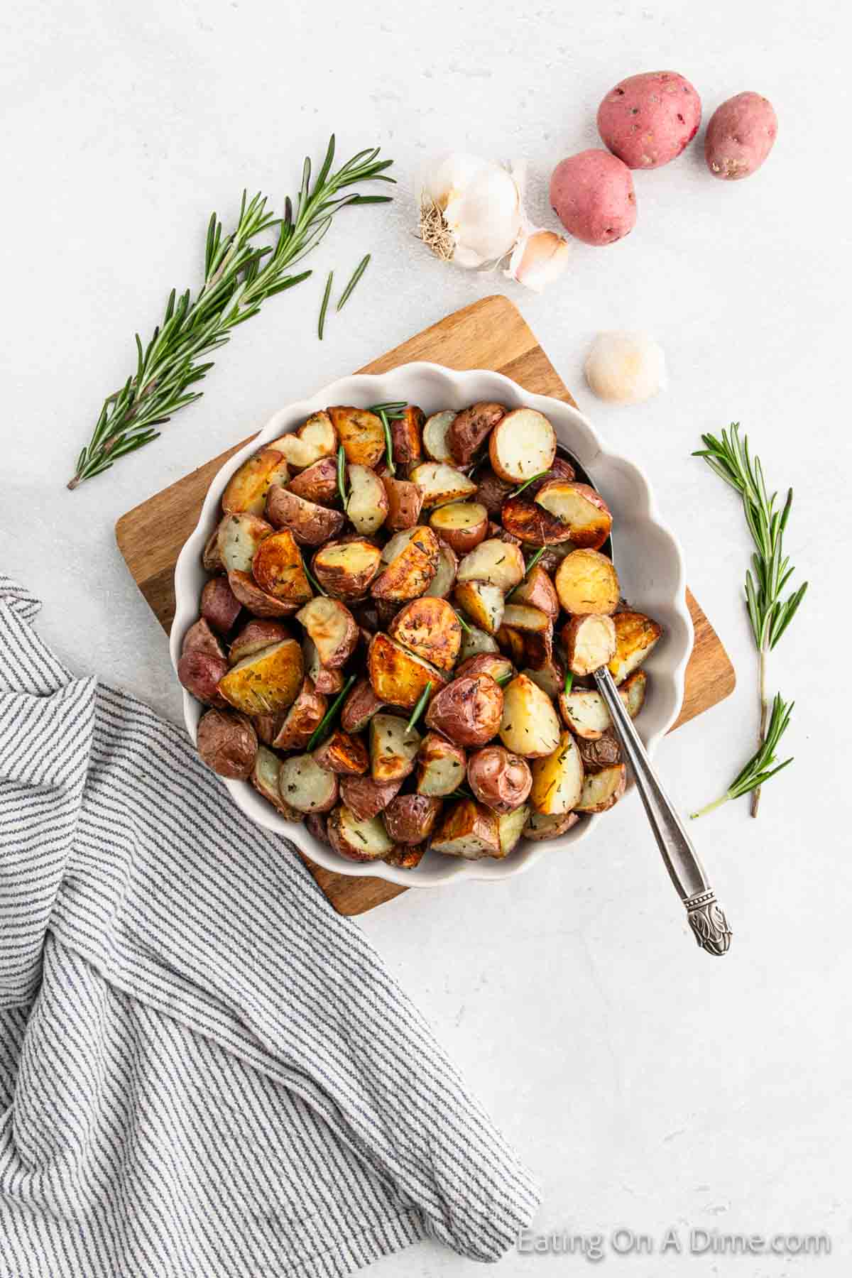 Roasted diced red potatoes in a bowl with fresh rosemary sprigs on the side