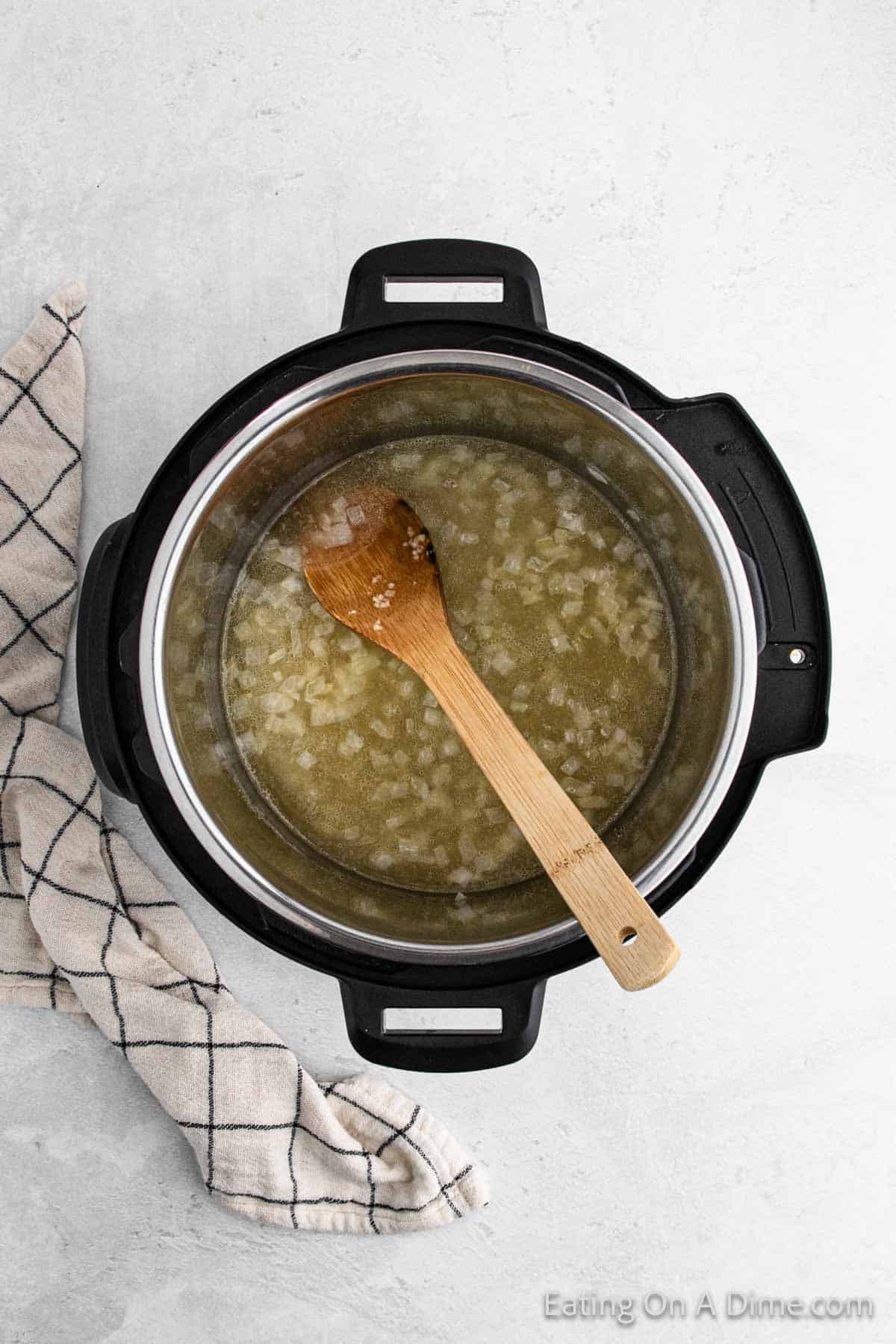 Chicken Broth poured over the chopped onions in the instant pot with a wooden spoon