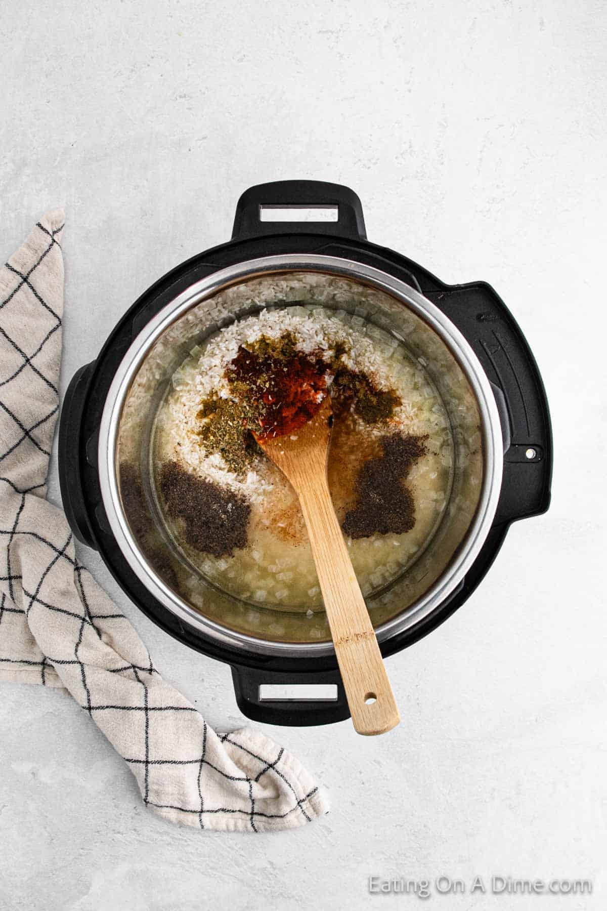 Spices with rice, broth and chopped onions in the instant pot